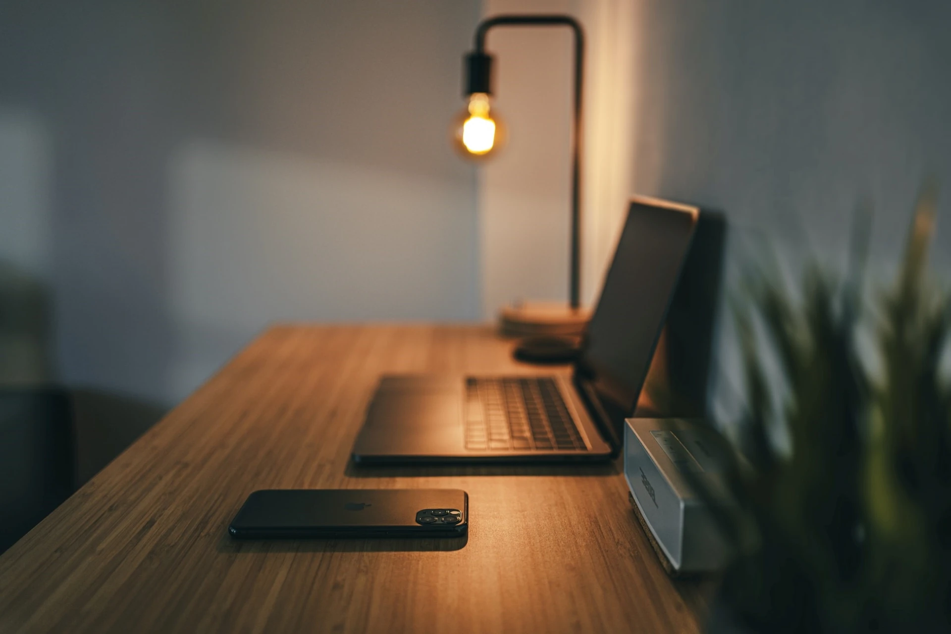 A macbook on a desk with a light hanging over